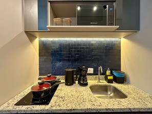 A kitchen with a microwave, coffee maker, and a sink. - Setin_2302 · Studio no 23º andar | 1 min do Metrô República (Santa Ifigênia)