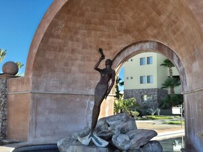 Eine Statue einer Frau, die auf Felsen unter einem Bogen steht.