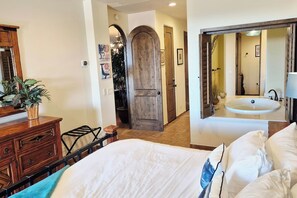 A bedroom with a bed, a dresser, a mirror, and a bathroom with a sink and mirror. - Elevated Bella Sirena Views: 2nd Floor Luxury (Puerto Peñasco)