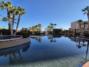 A swimming pool with palm trees and a clear sky. - Elevated Bella Sirena Views: 2nd Floor Luxury (Puerto Peñasco)