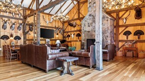 A rustic interior with a stone fireplace, leather furniture, and various animal skulls mounted on the walls. - The Bear Barn by Avantstay 150-acre Historic 1860 Barn Fire Pit + Mountain Views (Dover Plains)