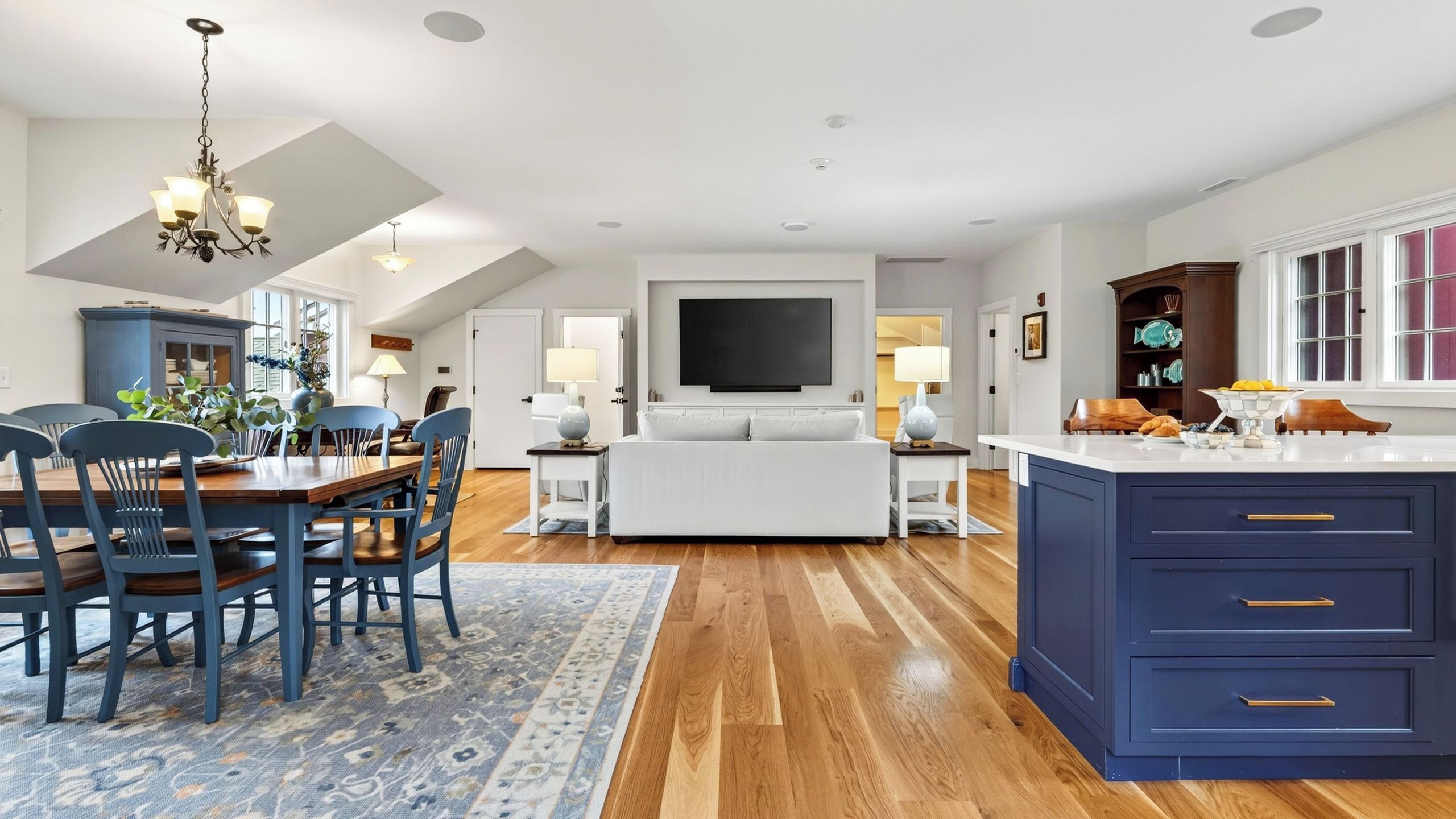 A spacious living area with a dining table, sofa, and a kitchen island with drawers.