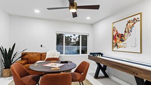 A modern living room with a brown leather sofa, a round coffee table, and a pool table. - The Royal Palms by Avantstay Pool + Hot Tub + Game Room + Fire Pit (Palm Springs)