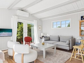 Un salon avec un canapé, deux fauteuils, une table basse et un téléviseur.