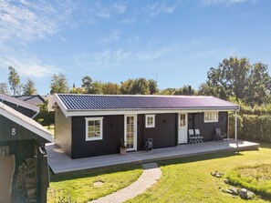 A single-story house with a dark exterior, a tiled roof, and a small porch with two chairs. - "Henryka" - 750m from the sea by Interhome (Gilleleje)