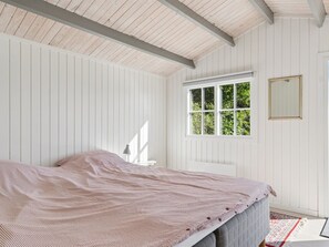 Un dormitorio con cama, ventana y espejo.