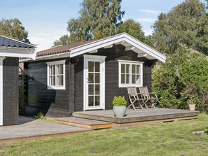 Una casa con terraza, una planta en maceta y mobiliario exterior.