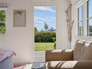 A room with a view of a garden, a door leading outside, a window with a view, and a piece of driftwood on the wall. - "Henryka" - 750m from the sea by Interhome (Gilleleje)