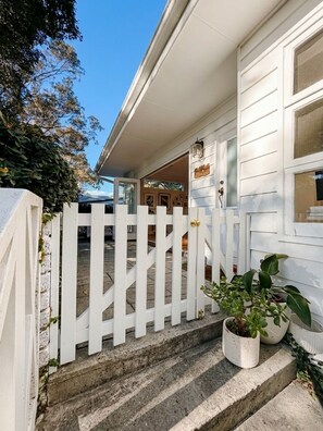 A white house with a white picket fence, a front door, and a small porch area. - Avalon home flat 5 minute stroll to village (Avalon Beach)