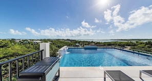Piscina com vista para a paisagem costeira e céu claro.
