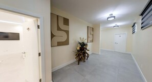 Ein Flur mit ebenem Boden, einer Tür links und einer Wand mit abstrakter Kunst.