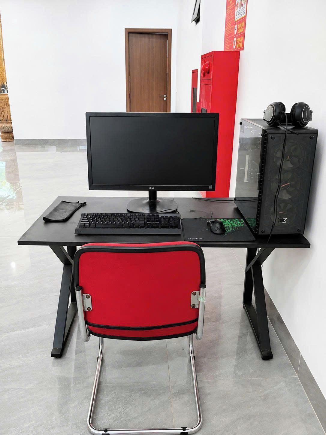 A workspace with a computer, keyboard, mouse, and headphones on a desk.