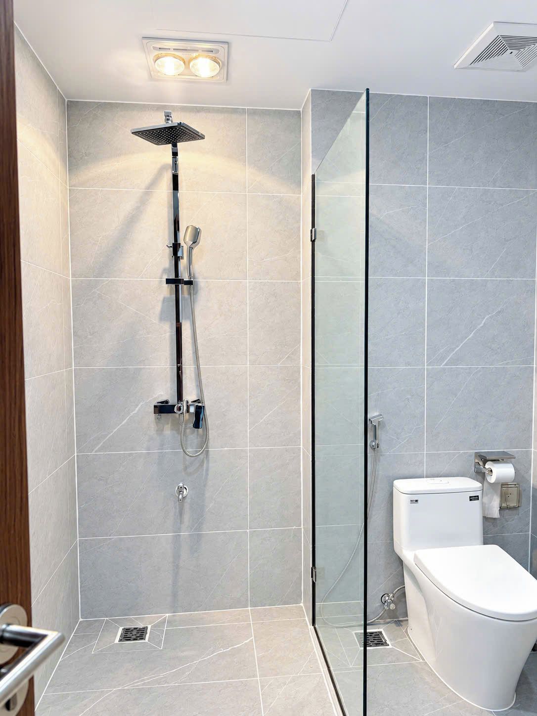 A modern bathroom with a glass shower enclosure, a toilet, and a bidet.