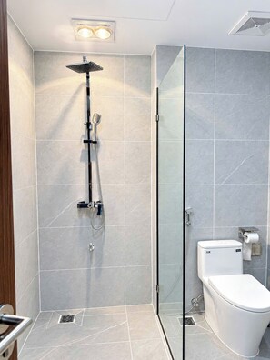 A modern bathroom with a glass shower enclosure, a toilet, and a bidet. - Nam Hai Hotel & Apartment (Vĩnh Phúc)