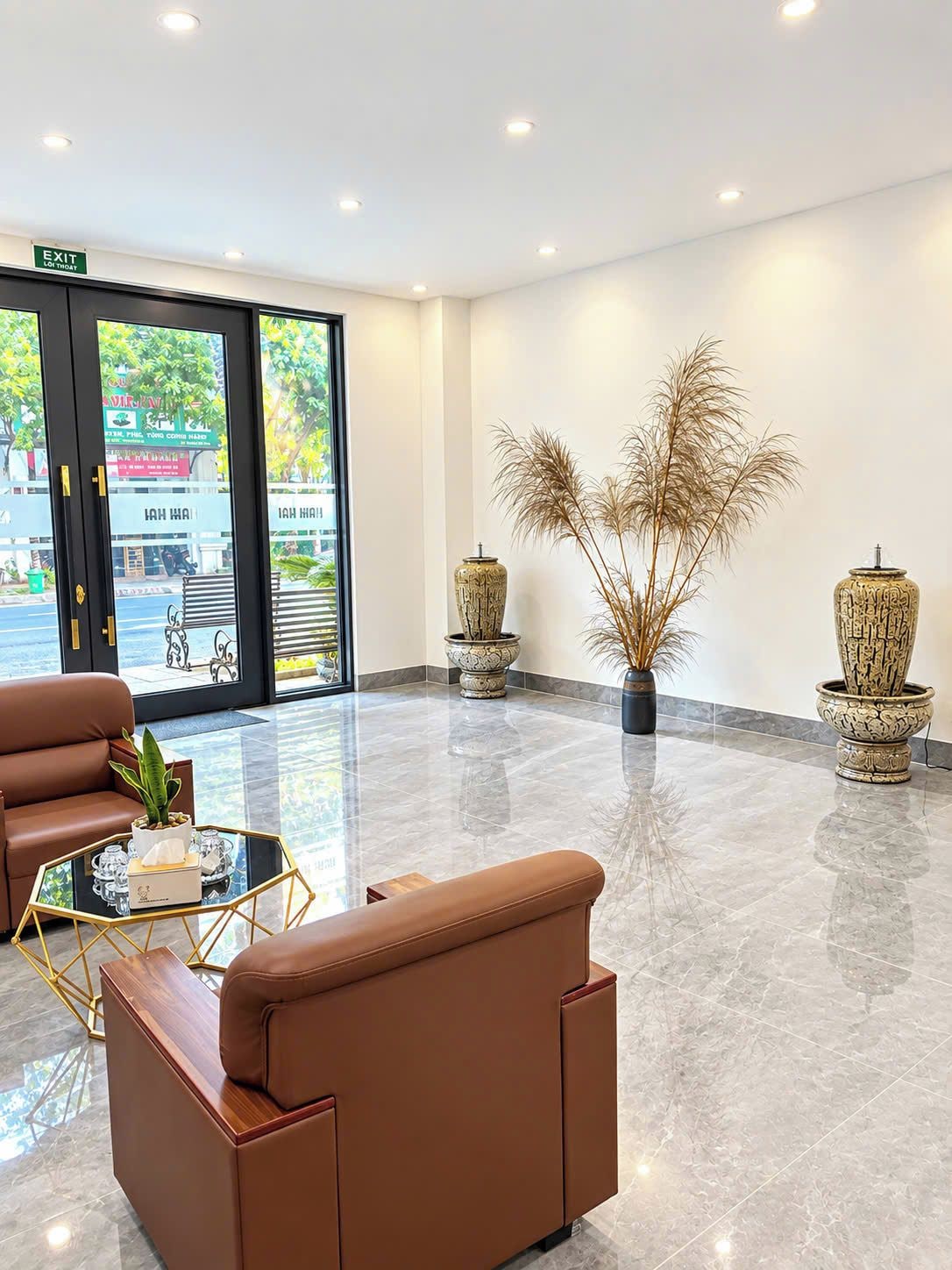 Een moderne lobby met lederen zitplaatsen, een glazen salontafel en decoratieve vazen.