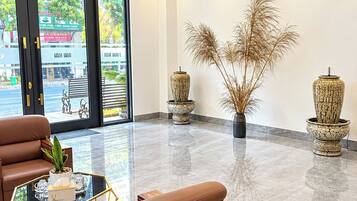 Een moderne lobby met lederen zitplaatsen, een glazen salontafel en decoratieve vazen.