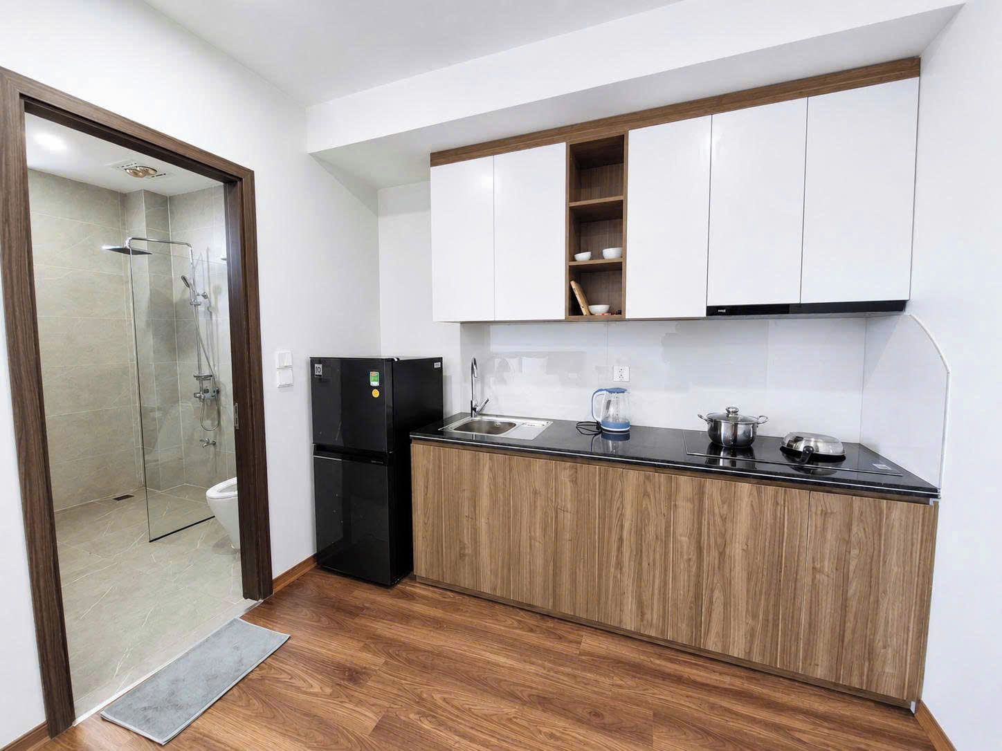 A compact kitchen with a built-in dishwasher, a coffee maker, and a kettle on the countertop.