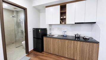 A compact kitchen with a built-in dishwasher, a coffee maker, and a kettle on the countertop.