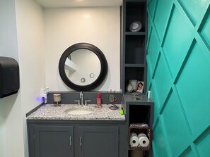 A bathroom with a granite countertop sink, a black-framed mirror, and a teal accent wall. - Terrific 3-bedroom building, fully furnished with AC and Heat in Kansas City. (Kansas City)