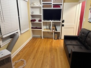 A living room with a sofa, a TV, and a storage unit with shelves. - Terrific 3-bedroom building, fully furnished with AC and Heat in Kansas City. (Kansas City)