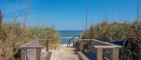 Un sendero de madera que lleva a un banco con vista a la playa.