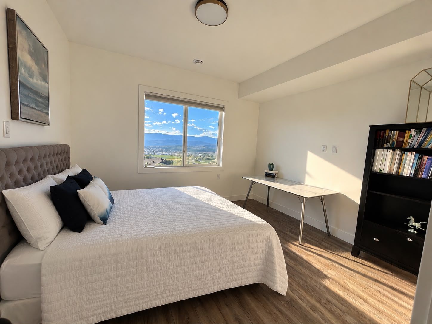 Un dormitorio con una cama grande, un escritorio y una estantería.