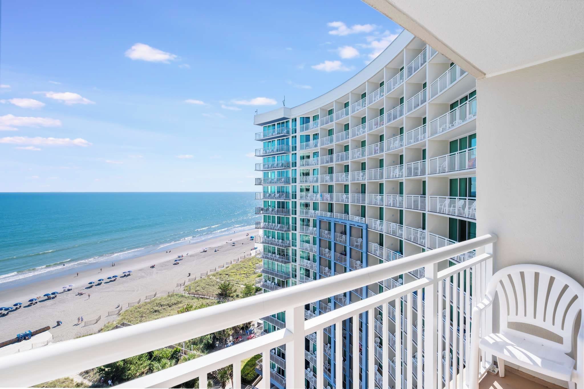 A high-rise hotel with multiple balconies overlooking a beach.