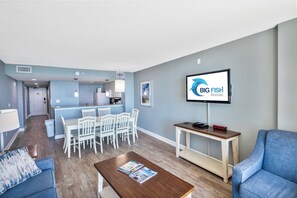 A modern living room with a dining area, a flat-screen TV, and a kitchen in the background. - Stunning View Amazing Oceanfront on the 12th Floor (North Myrtle Beach)