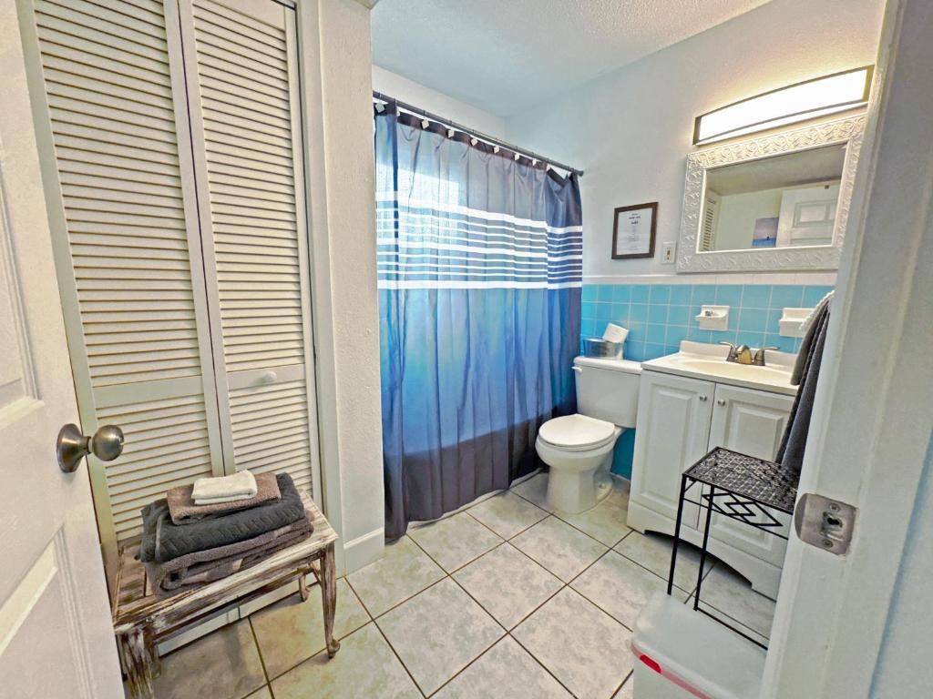 Un baño con inodoro, lavabo y cortina de ducha.