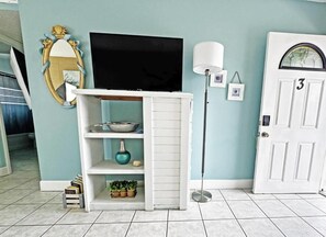 A room with a white entertainment unit, a flat-screen TV, a lamp, and a door with the number 3.