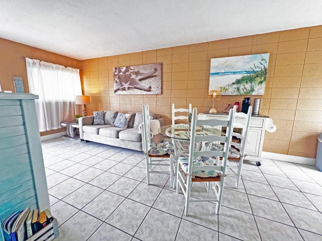 A living room with a sofa, chairs, a dining table, and artwork on the walls.
