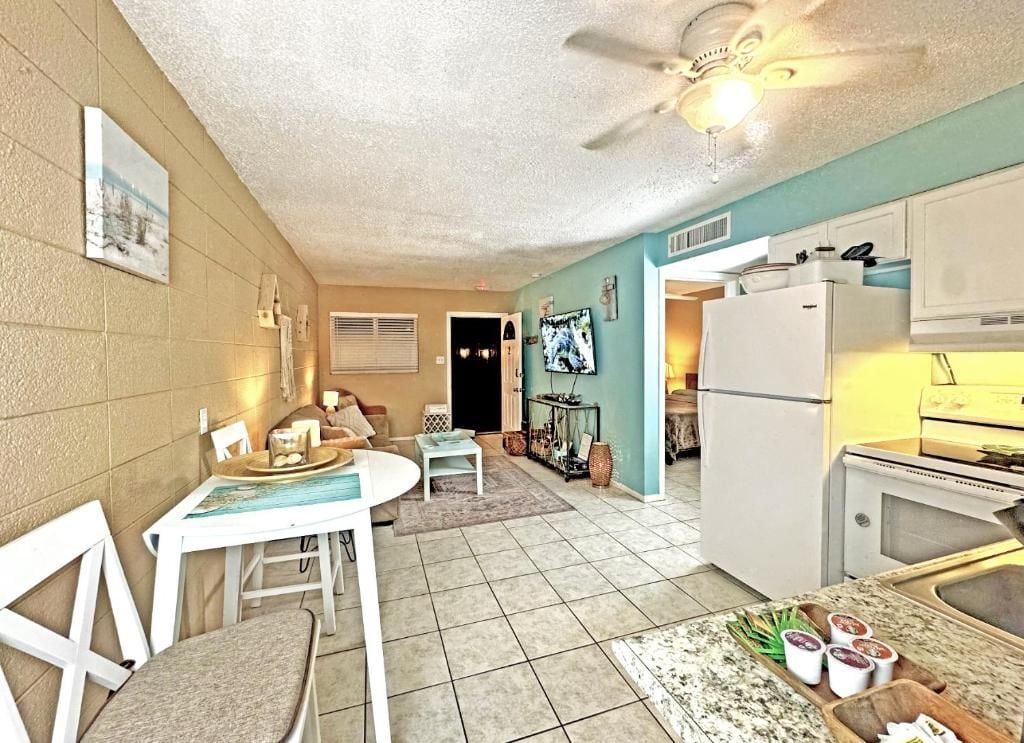 A compact kitchen with a refrigerator, microwave, and a dining area with a table and chairs.