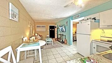 A compact kitchen with a refrigerator, microwave, and a dining area with a table and chairs.
