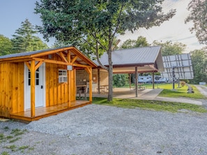 A wooden cabin with a covered porch and a picnic table. - Leo | Black Lake Glamping Dome (Hammond)