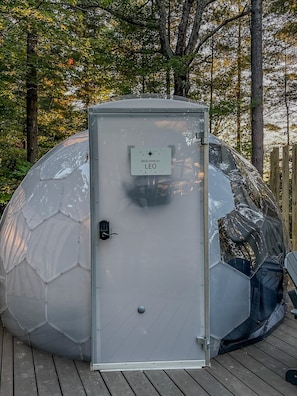 A metallic utility box with a sign that reads 'Welcome to LEO' on a wooden deck. - Leo | Black Lake Glamping Dome (Hammond)