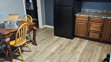 A kitchen with a black refrigerator, wooden cabinets, and a dining table with chairs.