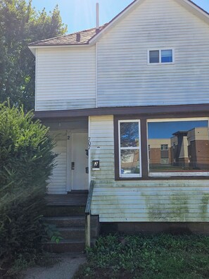 A two-story house with a front door, a small window, and a mailbox.