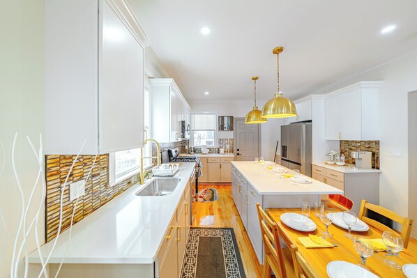 A modern kitchen with white cabinetry, a central island, and pendant lighting. - 82_Elegant 3BR Boston Home • 2 Baths + Parking • Near Red Line (Boston)