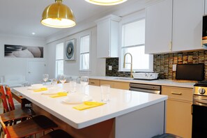 A modern kitchen with a central island, white cabinetry, a dishwasher, and a built-in oven. - 82_Elegant 3BR Boston Home • 2 Baths + Parking • Near Red Line (Boston)