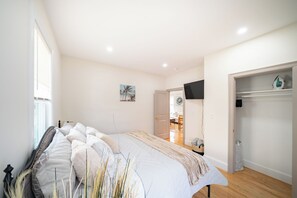 A bedroom with a bed, a television, and a wardrobe. - 82_Elegant 3BR Boston Home • 2 Baths + Parking • Near Red Line (Boston)
