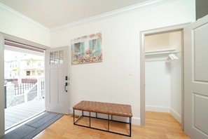 A hallway with a bench, a door, and a painting on the wall.
