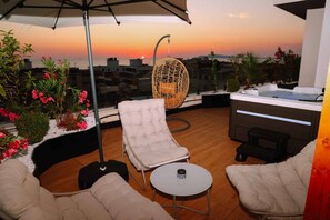 A rooftop terrace with a hanging chair, a sofa, a small table, and a hot tub. - Altamar Luxury Suites Penthouse - 104 (Golem)