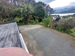 A rooftop with a gravel surface, surrounded by dense greenery and a view of a lake and mountains. - Willow Bay, Mahua Sound. Easy road & Beach access, tidal Beach launching/mooring (Mahau Sound)