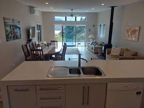 A modern kitchen with a large island, a dining area with a table and chairs, and a living area with a sofa and a television. - Willow Bay, Mahua Sound. Easy road & Beach access, tidal Beach launching/mooring (Mahau Sound)