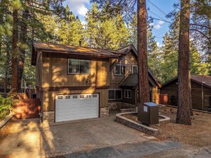 A two-story wooden house with a garage, surrounded by tall trees. - The Edgewood Retreat (South Lake Tahoe)