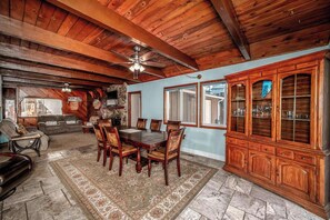 A spacious dining area with a large wooden table and chairs, a ceiling fan, and a view through a window. - The Edgewood Retreat (South Lake Tahoe)