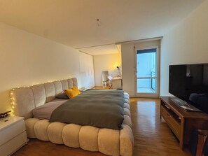Ein modernes Schlafzimmer mit einem großen Bett, einem Nachttisch und einem Fernseher.