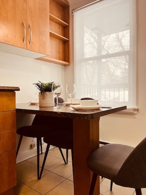 A kitchen with wooden cabinets, a marble countertop, two chairs, and a window with a view of trees. - Modern apartment in the heart of Gatineau. (Gatineau)