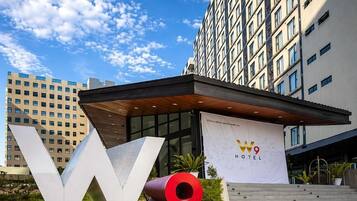 Entrada de un hotel con un cartel grande que dice 'W9', fachada de edificio moderna y cielo despejado.