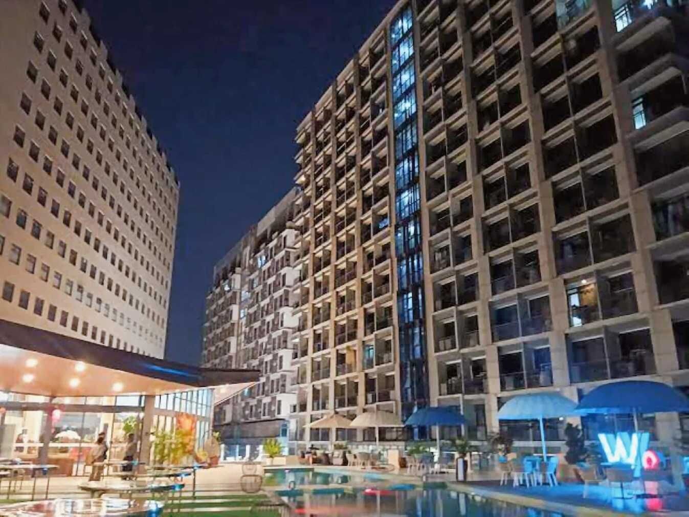 Un hotel de gran altura con varias plantas, una piscina y zonas de estar al aire libre.